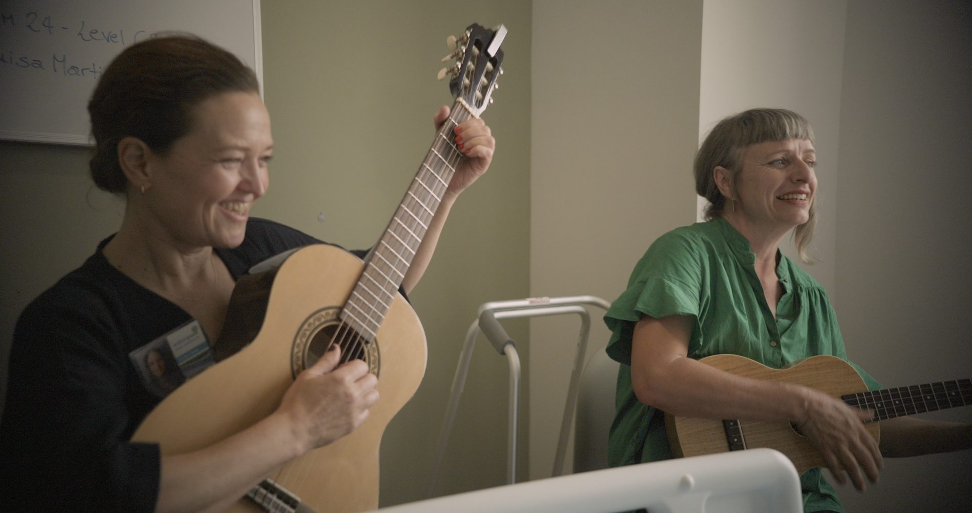 Two musicians smiling and playing guitar